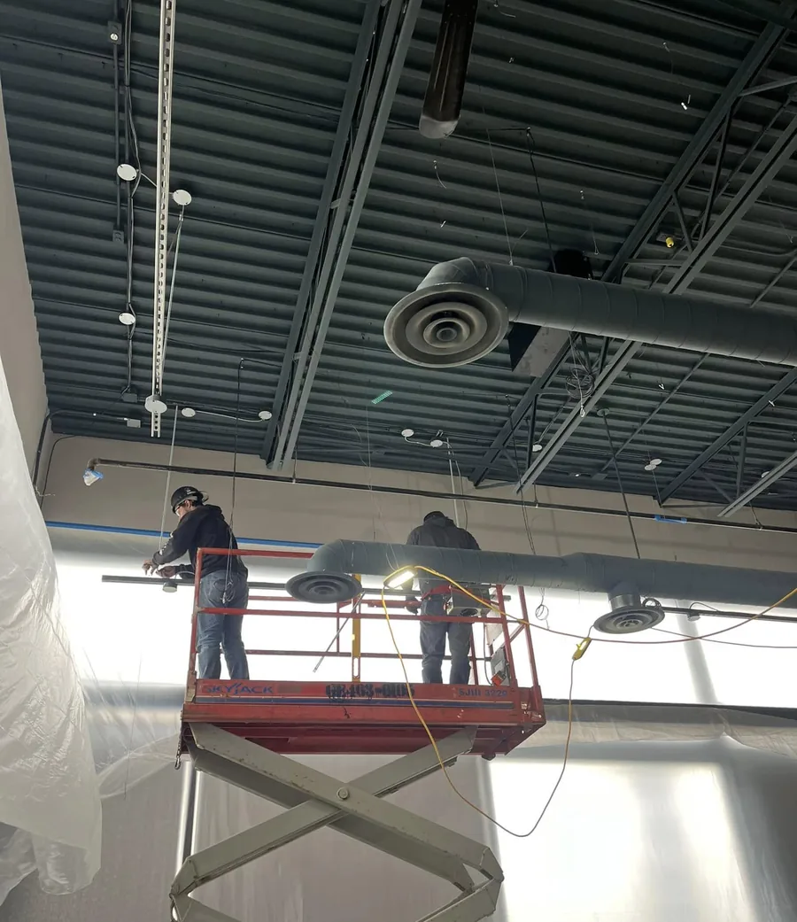 Aviation Mechanical technicians servicing rooftop equipment from a scissor lift
