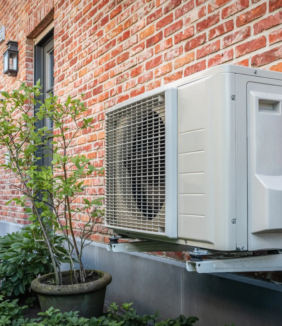 Air-source heat pump mounted on the exterior wall of a home