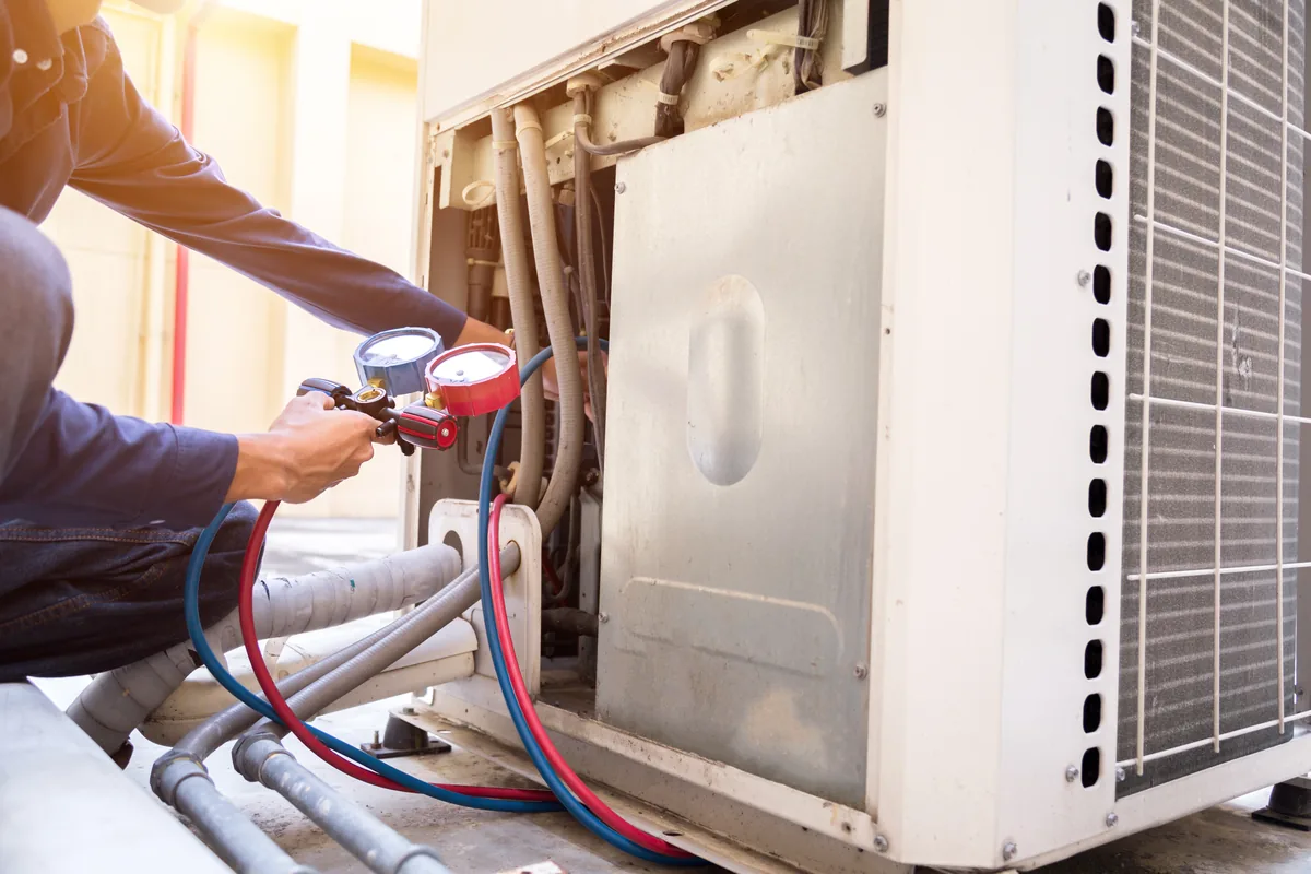 Technician connecting manifold gauges to an outdoor condensing unit