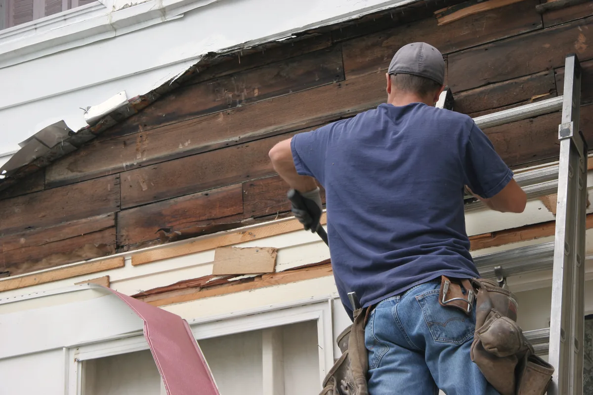 Tradesperson fitting metal flashing at a roof edge
