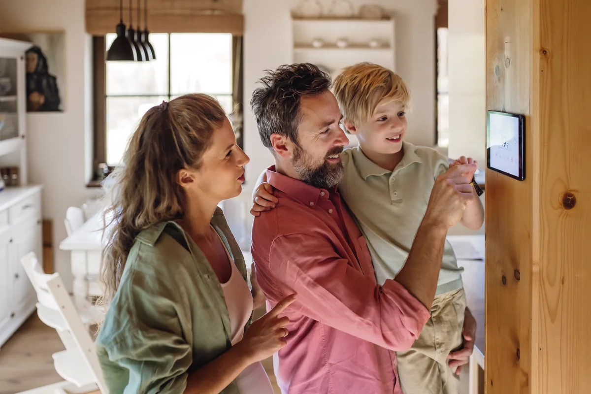 A family adjusting a wall thermostat together