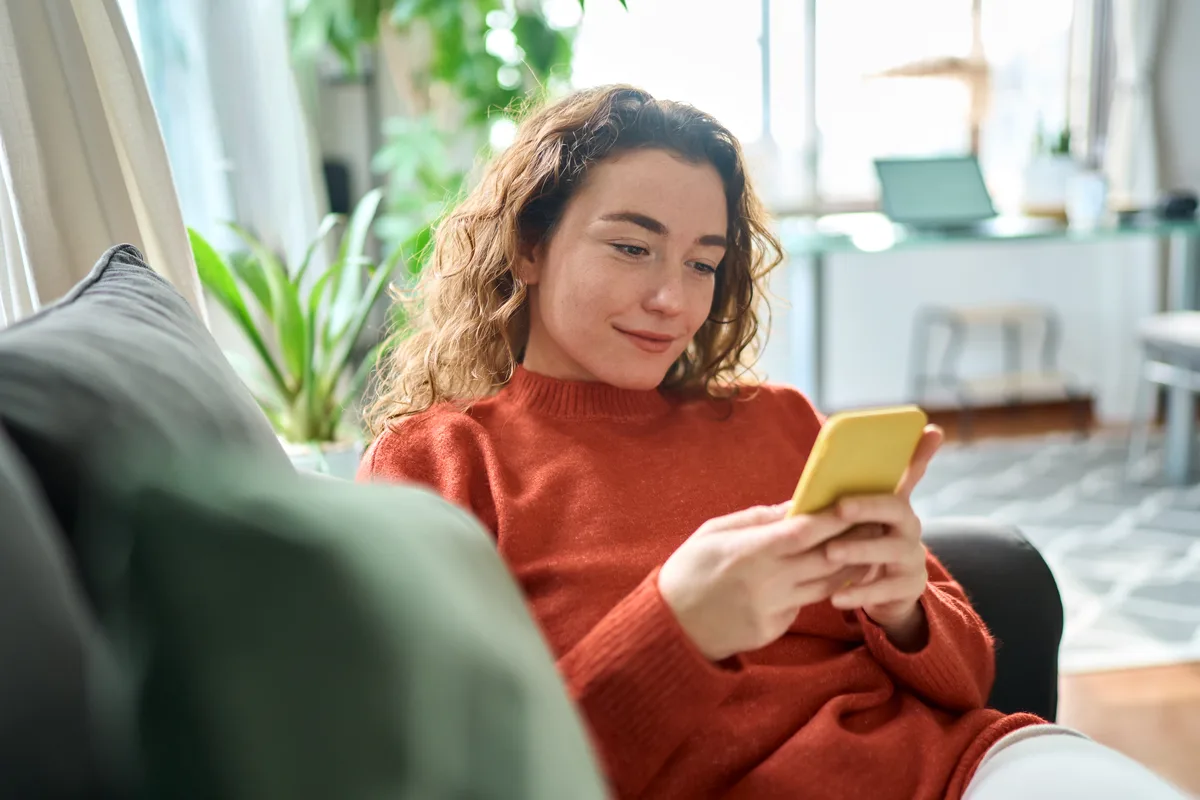 Homeowner at home using a phone to book a gas fireplace repair visit