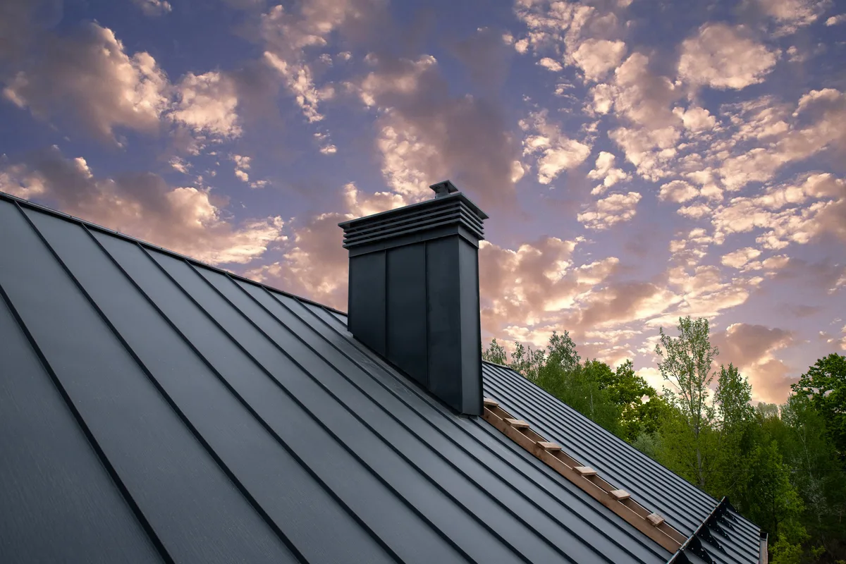 Sheet-metal chimney chase with a vented cap where a fireplace flue terminates above the roofline