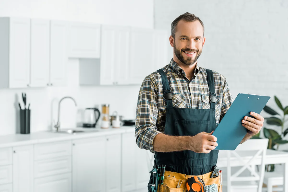 HVAC technician with a service checklist in a kitchen