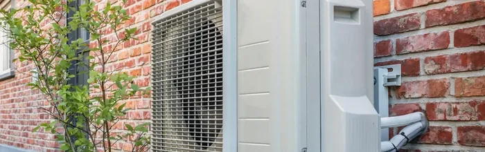 Outdoor heat pump unit mounted on the exterior wall of a home